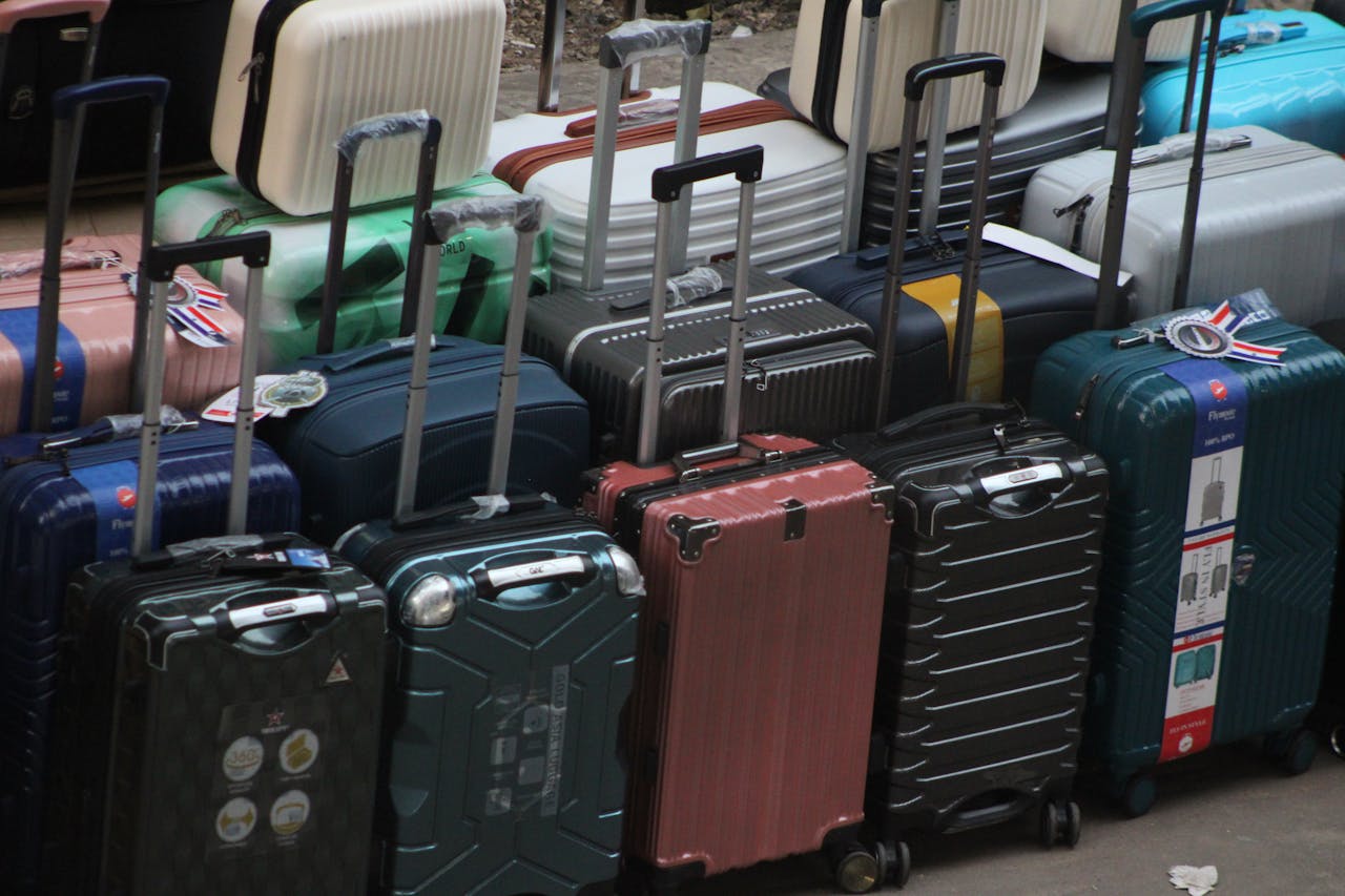 A sculptural pile of colorful vintage suitcases stacked high, representing lost and unclaimed airline luggage